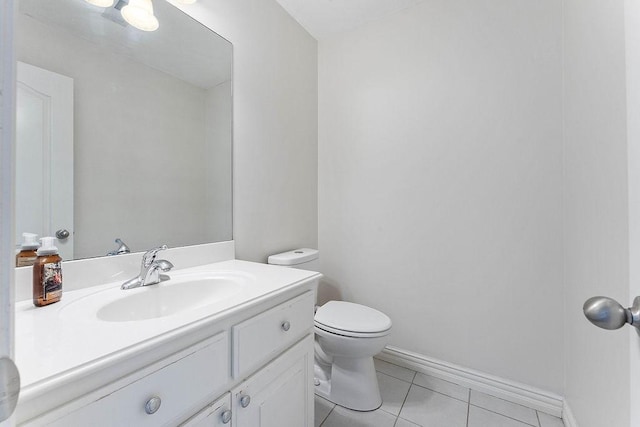 half bathroom with toilet, tile patterned floors, baseboards, and vanity