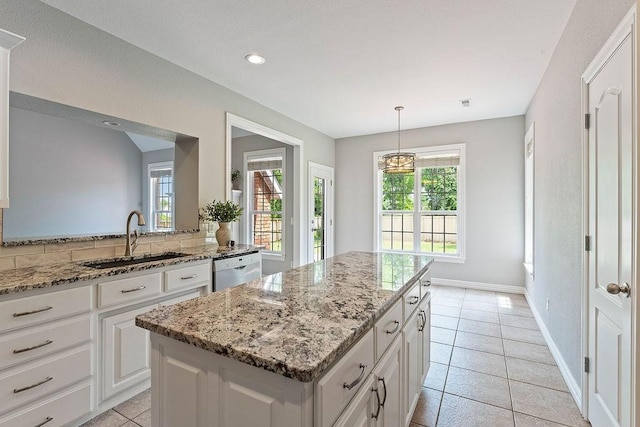 kitchen with a kitchen island, white cabinetry, light stone counters, and a sink