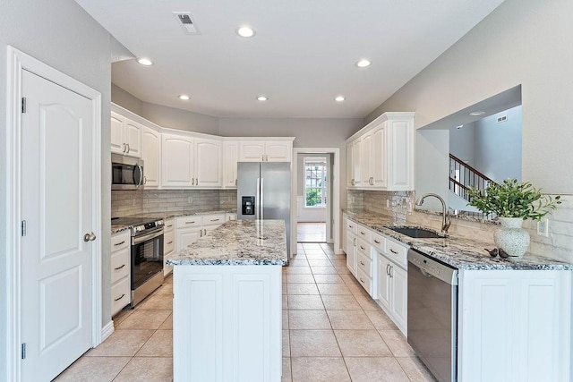 kitchen featuring a sink, appliances with stainless steel finishes, decorative backsplash, and a center island