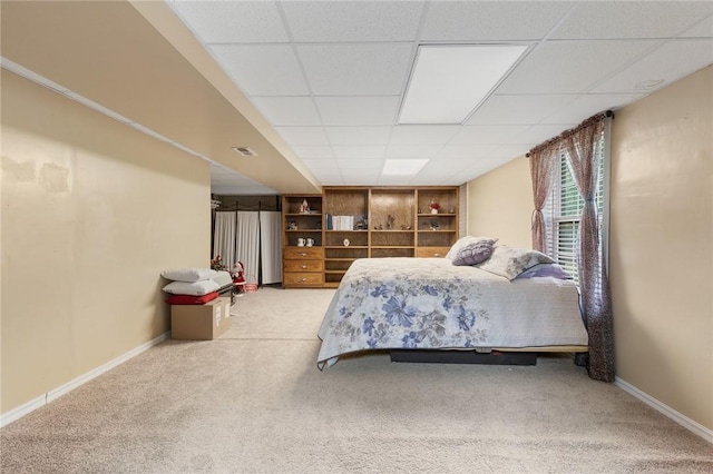 carpeted bedroom featuring baseboards and a paneled ceiling