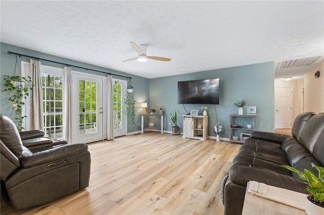 living room featuring ceiling fan, visible vents, baseboards, and wood finished floors