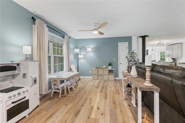 living room with baseboards, a ceiling fan, and light wood-type flooring