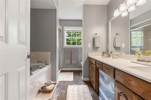 bathroom with double vanity, a bath, a stall shower, a sink, and toilet
