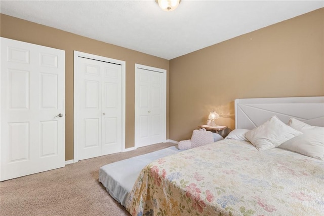 bedroom with carpet floors, baseboards, and two closets