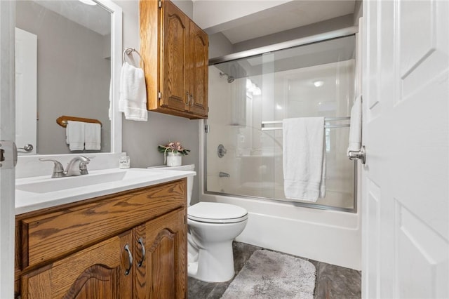 bathroom with vanity, bath / shower combo with glass door, and toilet