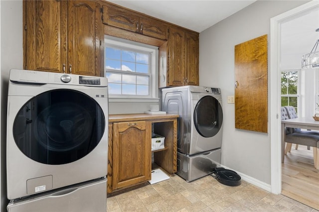 clothes washing area featuring baseboards and cabinet space