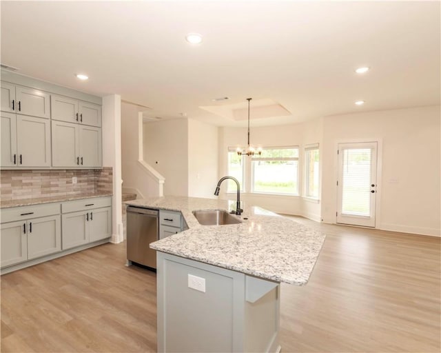 kitchen with light wood-style floors, tasteful backsplash, a sink, and dishwasher