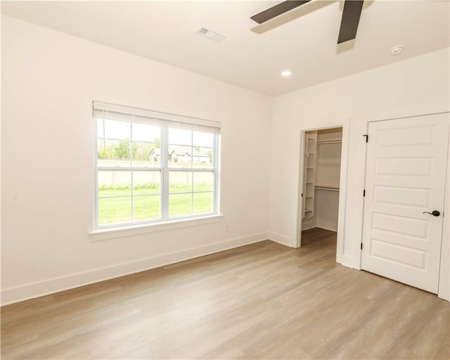 unfurnished bedroom featuring light wood-style flooring, recessed lighting, baseboards, a spacious closet, and visible vents