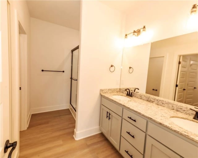 bathroom featuring double vanity, a sink, baseboards, and wood finished floors
