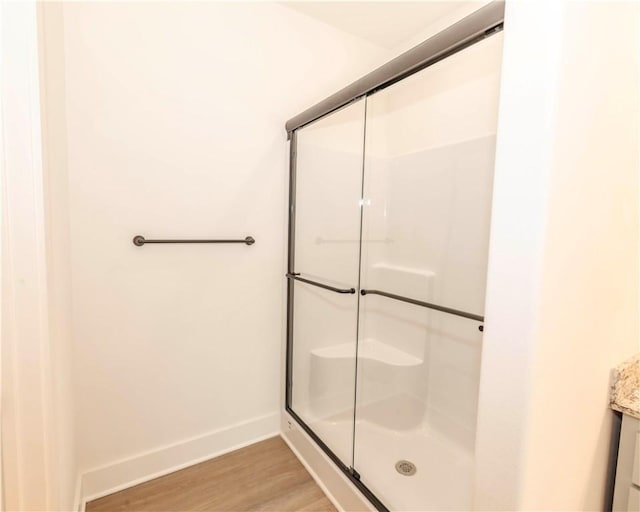 bathroom with vanity, baseboards, wood finished floors, and a stall shower