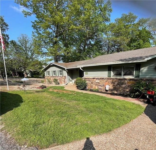 view of front of home featuring a shingled roof, a front yard, and stone siding