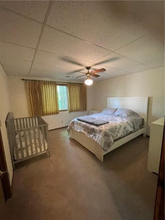 bedroom featuring a ceiling fan, carpet, and a drop ceiling