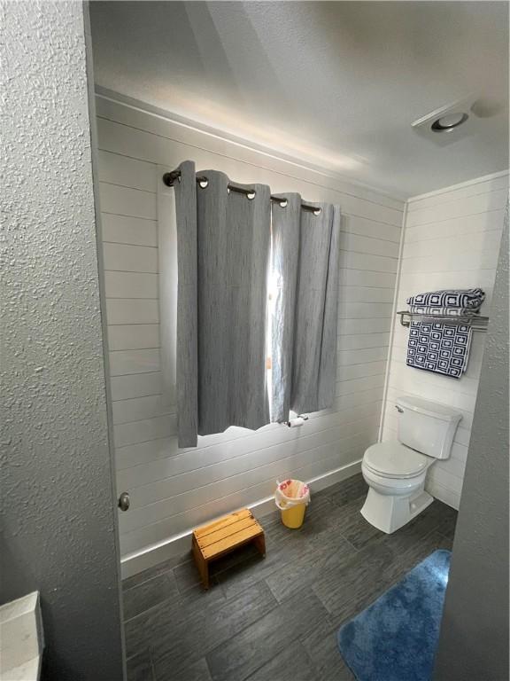 bathroom featuring baseboards, wood finished floors, and toilet