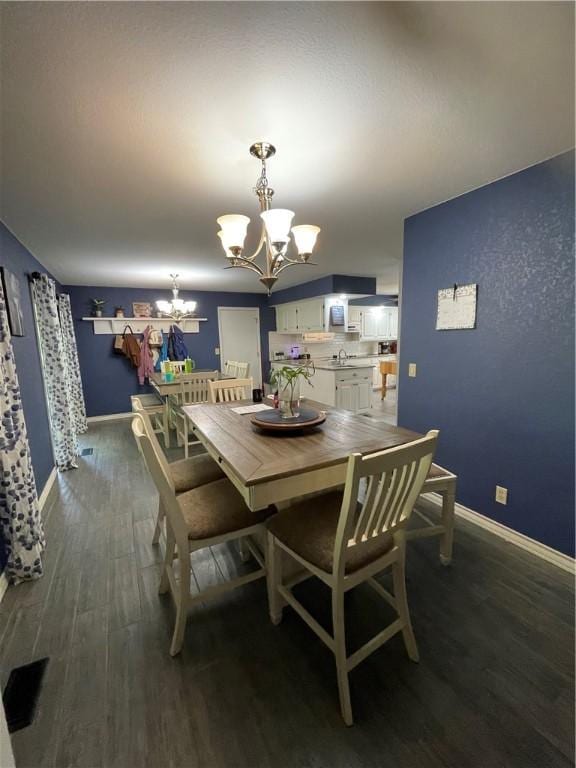 dining space with an inviting chandelier, dark wood finished floors, and baseboards