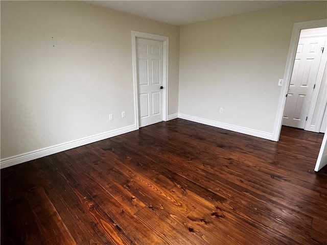 unfurnished room featuring baseboards and dark wood-style flooring