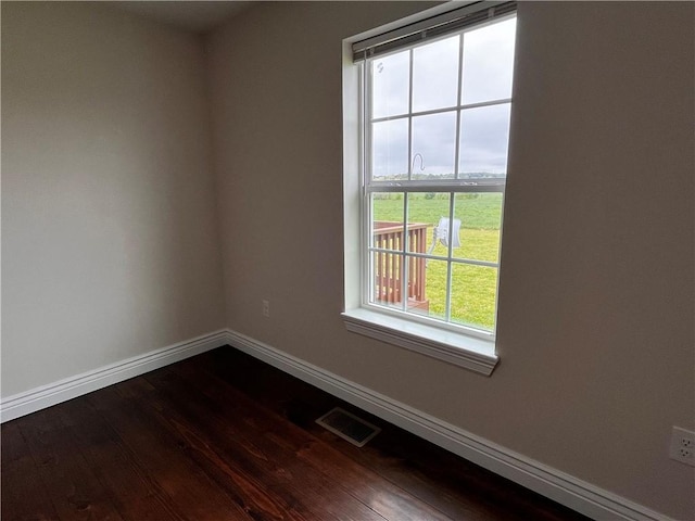 empty room with baseboards, dark wood-type flooring, and visible vents
