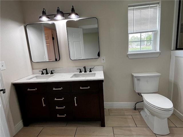 full bath with baseboards, a sink, double vanity, and toilet