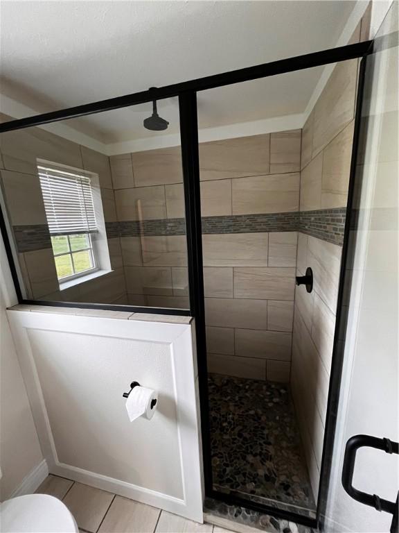 full bath featuring tile patterned floors, a stall shower, and toilet