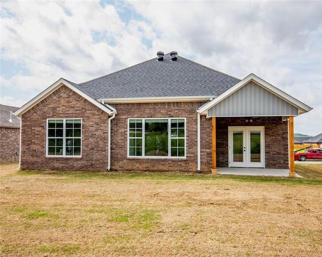 rear view of house featuring a lawn, brick siding, and french doors