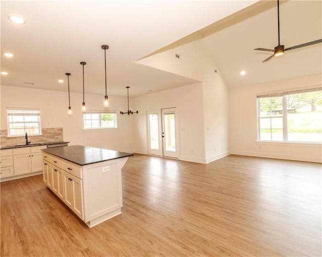 kitchen featuring recessed lighting, a sink, dark countertops, and light wood-type flooring