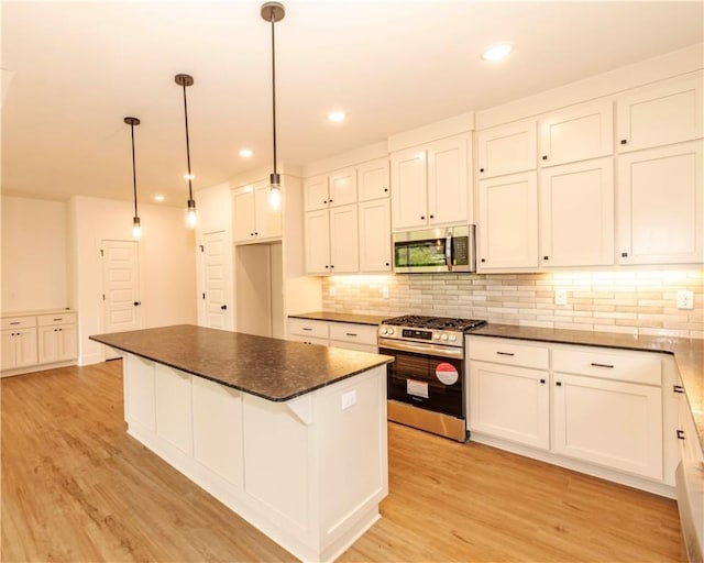 kitchen featuring light wood-type flooring, backsplash, dark countertops, and stainless steel appliances
