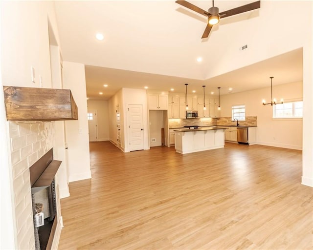 unfurnished living room featuring a fireplace, light wood-type flooring, a sink, baseboards, and recessed lighting