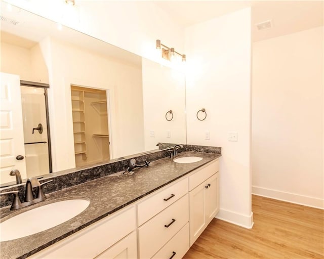 bathroom featuring baseboards, a sink, wood finished floors, and a shower stall