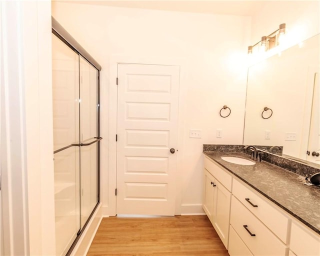 bathroom with a stall shower, baseboards, wood finished floors, and vanity