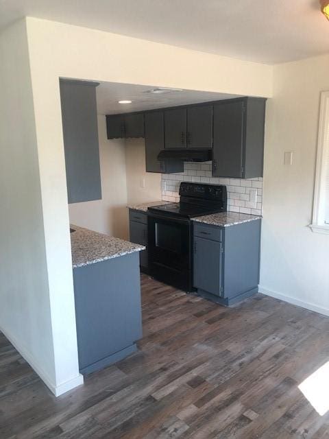 kitchen featuring decorative backsplash, black range with electric cooktop, dark wood-style flooring, under cabinet range hood, and light stone counters
