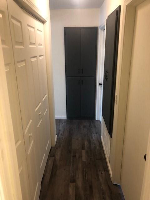 corridor with baseboards and dark wood finished floors