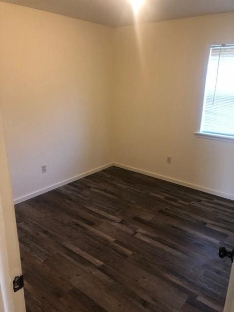 empty room with baseboards and dark wood-style floors