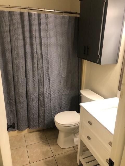 full bath featuring vanity, tile patterned floors, toilet, and curtained shower
