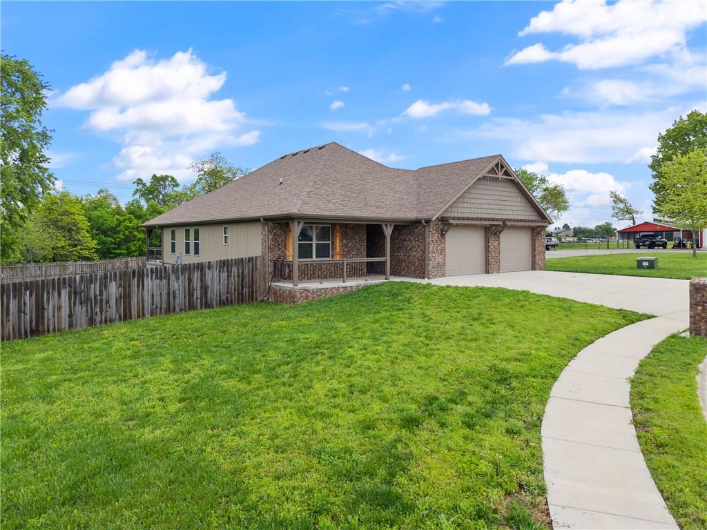 ranch-style home with covered porch, fence, brick siding, driveway, and a front lawn