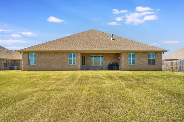back of house with a lawn, fence, and brick siding