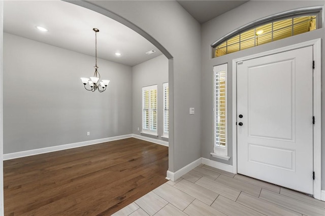 foyer entrance featuring baseboards, recessed lighting, a chandelier, arched walkways, and light wood finished floors