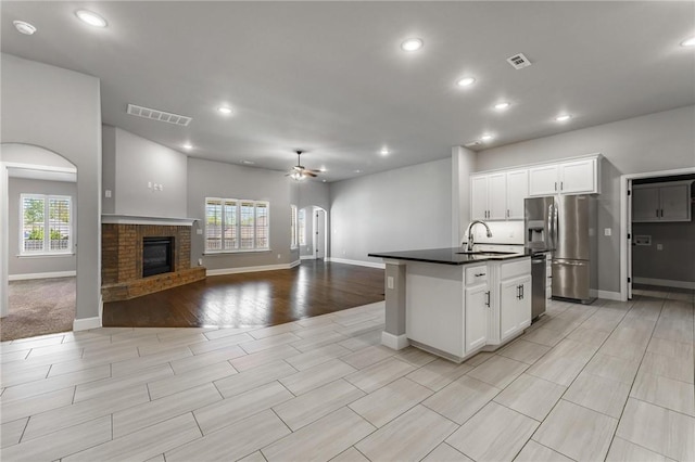kitchen with ceiling fan, appliances with stainless steel finishes, dark countertops, a sink, and visible vents