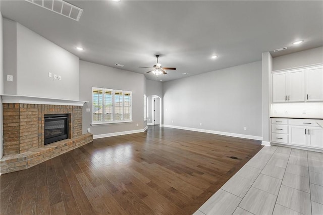 unfurnished living room with baseboards, a ceiling fan, a brick fireplace, and recessed lighting