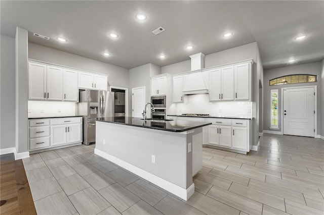kitchen featuring dark countertops, appliances with stainless steel finishes, visible vents, and tasteful backsplash
