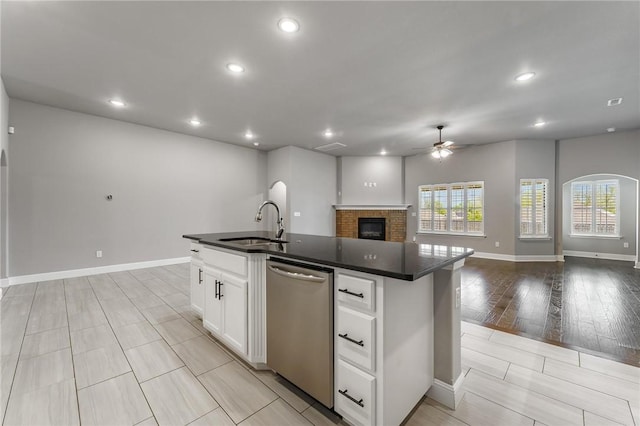 kitchen with dark countertops, open floor plan, ceiling fan, a sink, and dishwasher