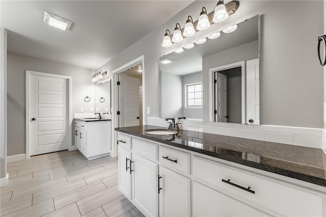 full bath featuring visible vents, a sink, two vanities, and wood finish floors