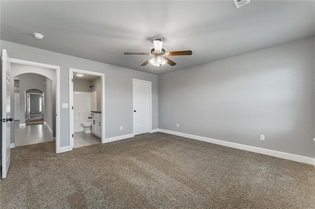 unfurnished bedroom featuring visible vents, arched walkways, baseboards, ensuite bathroom, and carpet flooring
