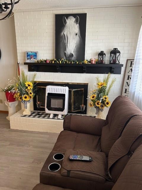 living area with baseboards, a brick fireplace, and wood finished floors