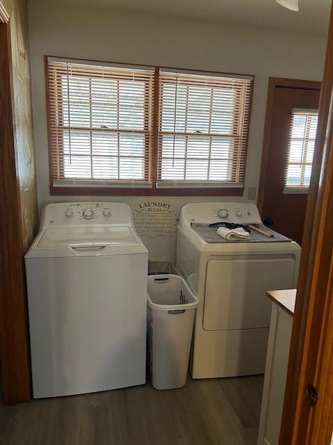 clothes washing area with laundry area, wood finished floors, and washing machine and clothes dryer