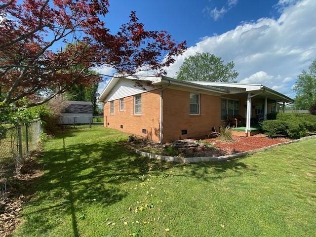 view of home's exterior featuring a lawn, brick siding, fence, and crawl space