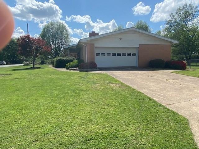 view of side of home featuring a lawn, an attached garage, a chimney, and concrete driveway