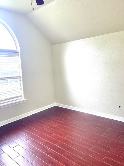 spare room featuring baseboards, ceiling fan, wood finished floors, and lofted ceiling