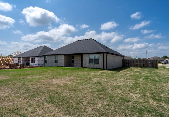 rear view of house featuring fence and a yard