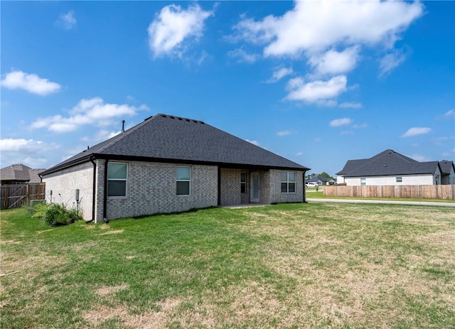 back of property with a lawn, brick siding, and fence