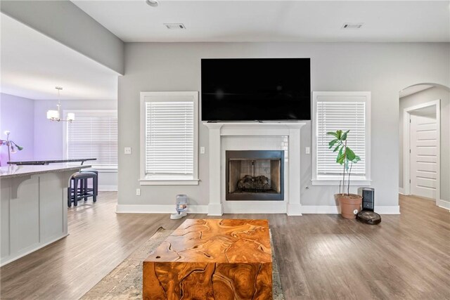 living room with a fireplace, a notable chandelier, wood finished floors, and visible vents