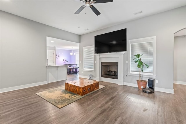 living room featuring visible vents, wood finished floors, a fireplace, baseboards, and a ceiling fan